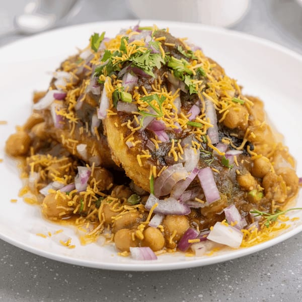 A plate of Mawa House's Indian chaat, topped with chickpeas, onions, cilantro, and crispy noodles.